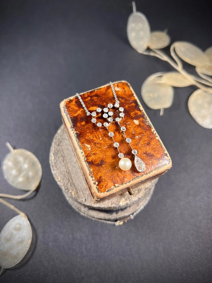 An antique diamond and pearl double drop pendant necklace, on an antique box