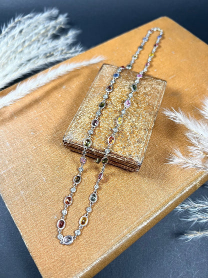 A coloured sapphire and diamond set necklace in platinum and gold, on an antique box and antique book