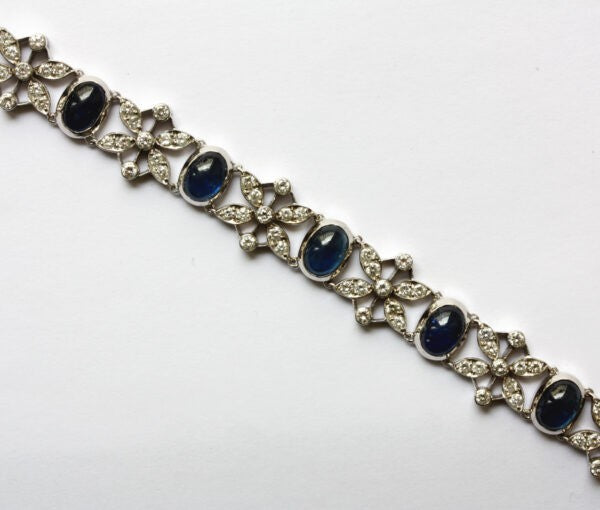 Vintage 15ct Sapphire and Diamond Bracelet; A white gold bracelet with eleven cabochon-cut sapphires alternated with 2.50cts diamond set flowers, Circa 1950