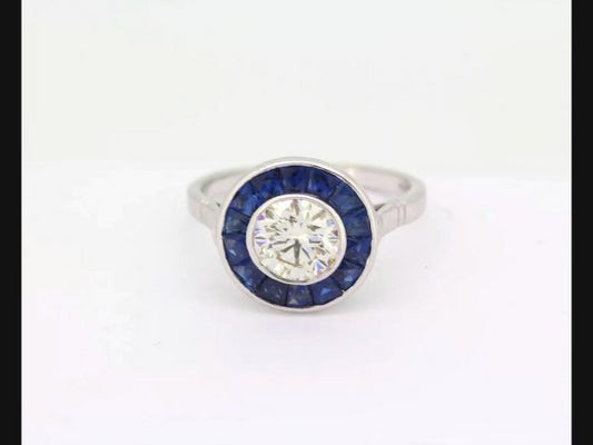 Vintage Art Deco Style Sapphire and Diamond Calibre Set Ring; round cut 1.21ct diamond encircled by sapphires.
