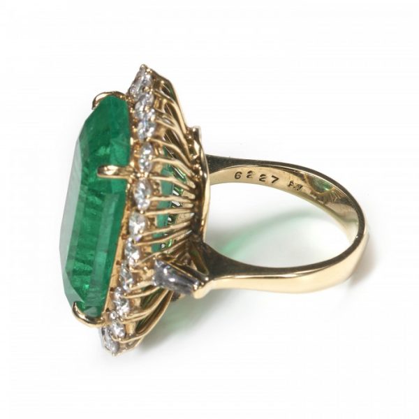 Vintage Colombian Emerald and Diamond Cluster Ring; 21.00 carat emerald-cut emerald surrounded by 2.20 carats of round brilliant-cut diamonds, in 18ct yellow gold, Circa 1980, with a GCS certificate