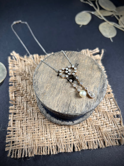 An antique diamond and pearl double drop pendant necklace, on a wooden spool