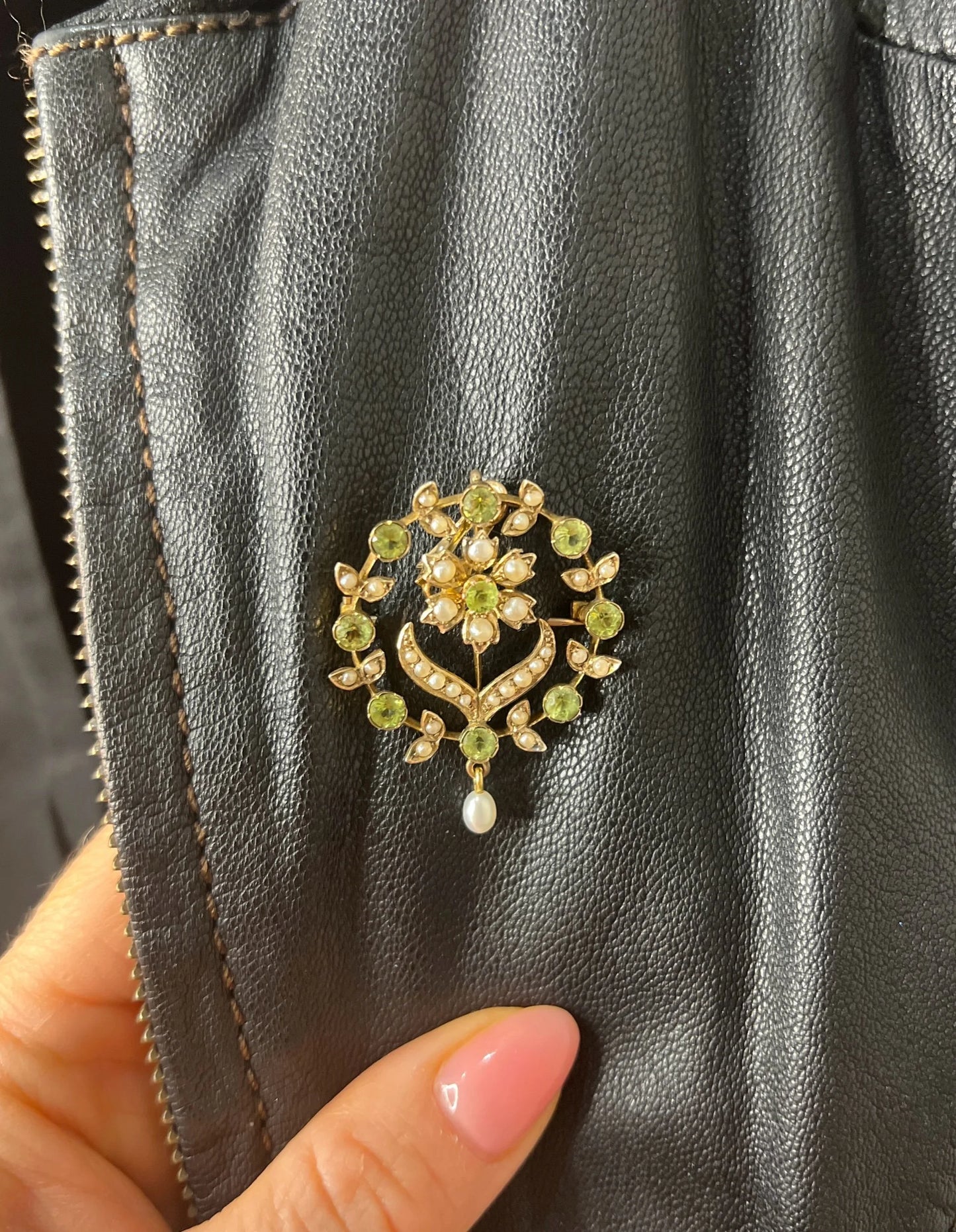 A peridot and pearl floral circle brooch/pendant in yellow gold, modelled on a black jacket