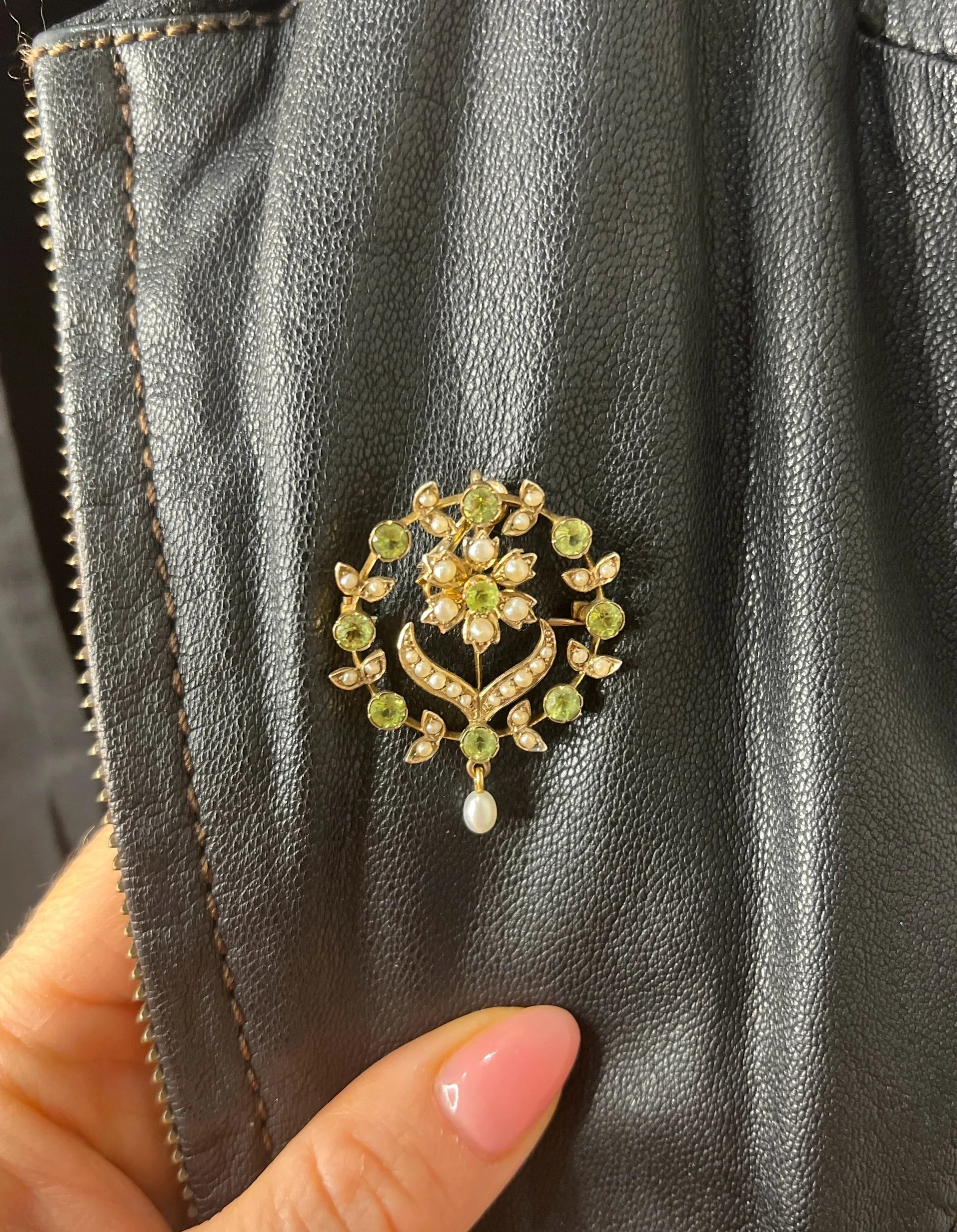 A peridot and pearl floral circle brooch/pendant in yellow gold, modelled on a black jacket