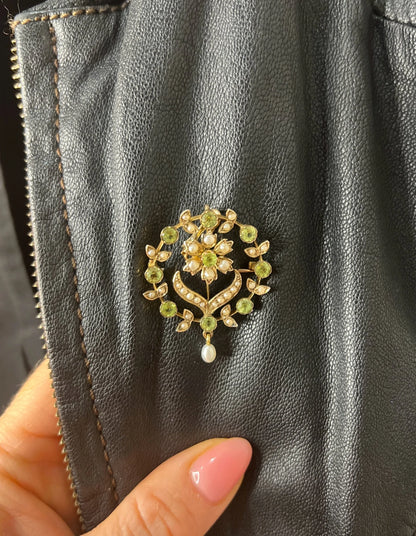 A peridot and pearl floral circle brooch/pendant in yellow gold, modelled on a black jacket