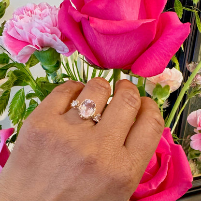 A three stone oval morganite and diamond ring in yellow gold, modelled on a hand