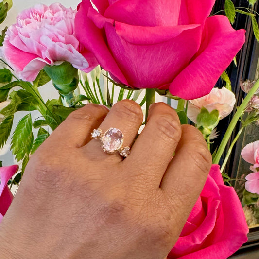 A three stone oval morganite and diamond ring in yellow gold, modelled on a hand