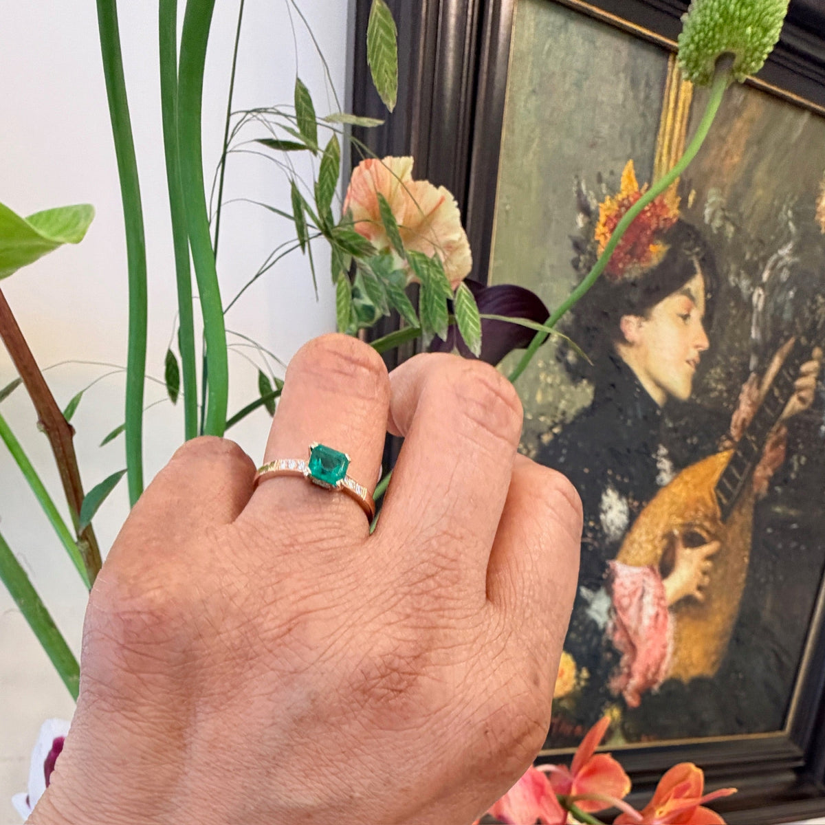A step cut emerald ring with diamond shoulders, in yellow gold, modelled on a hand