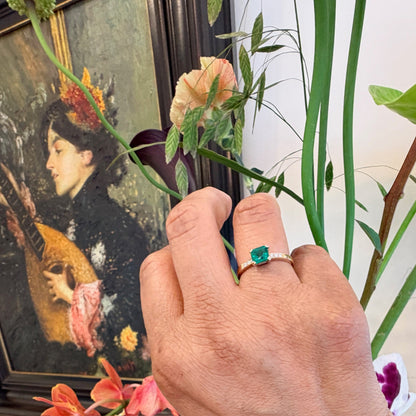 A step cut emerald ring with diamond shoulders, in yellow gold, modelled on a hand