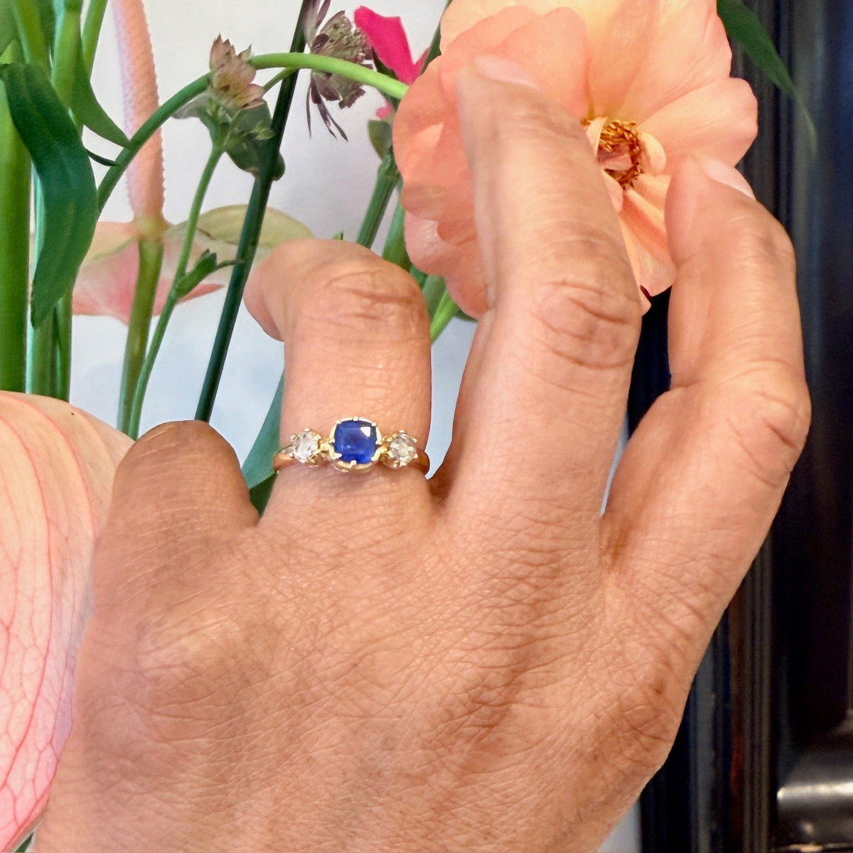 A sapphire and rose cut diamond three stone ring in yellow gold, modelled on a hand