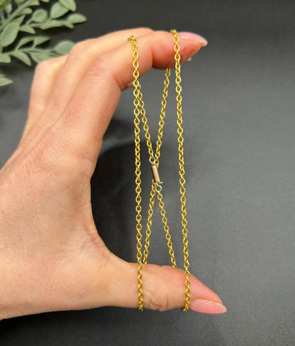 A yellow gold trace link chain necklace, held in a hand