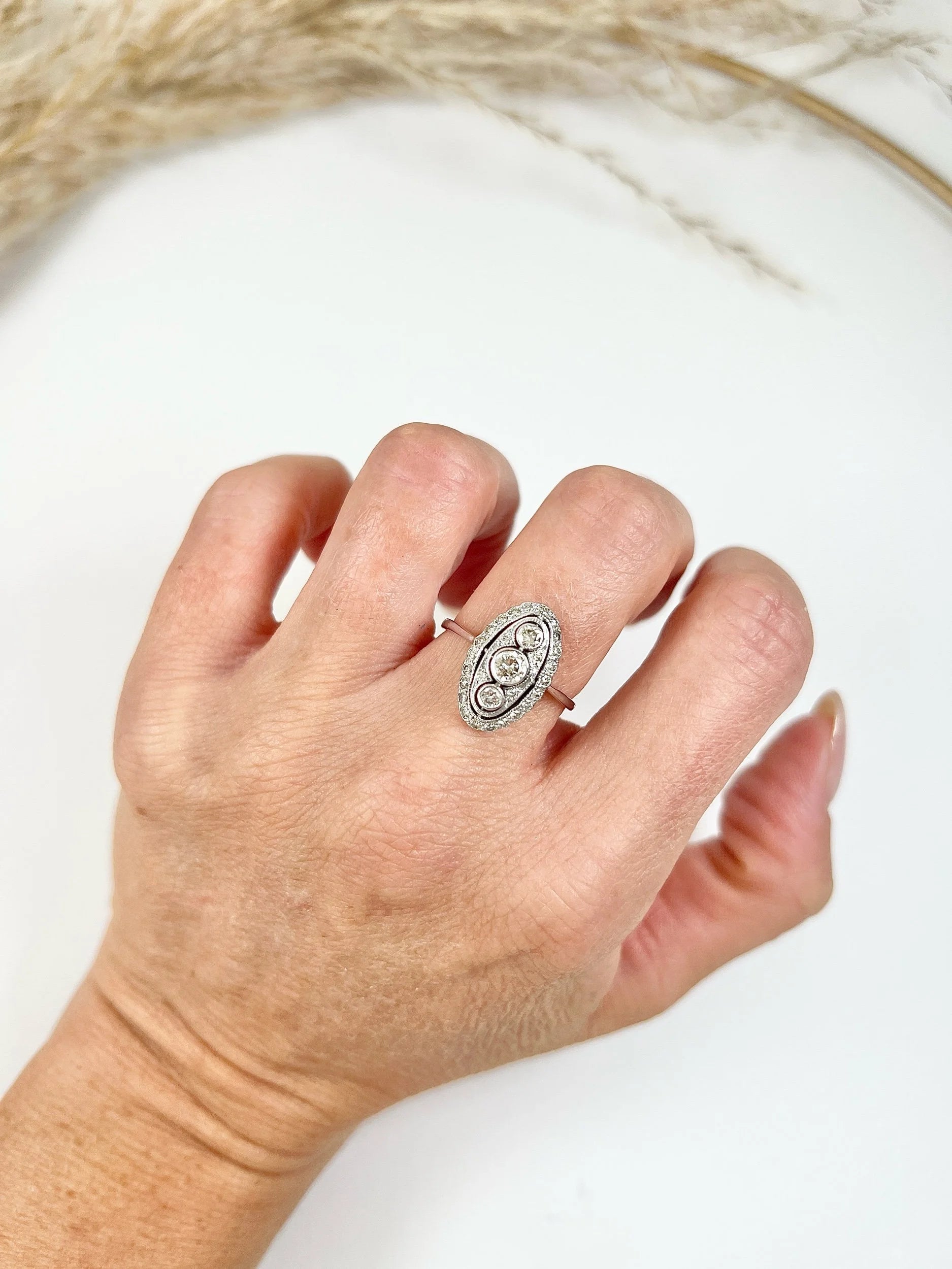 Antique 18 Carat White Gold Three Stone Diamond Oval Halo Ring, Circa 1910