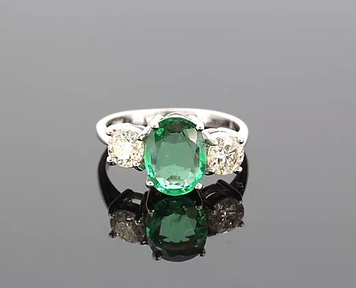 Vintage Emerald and Diamond Three-Stone Ring; featuring a 2.80ct oval-cut emerald flanked by two diamonds totaling 1.00ct, Four-claw set, 18ct white gold.