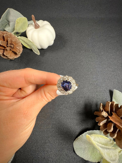 A round sapphire and diamond cluster ring, held in a hand