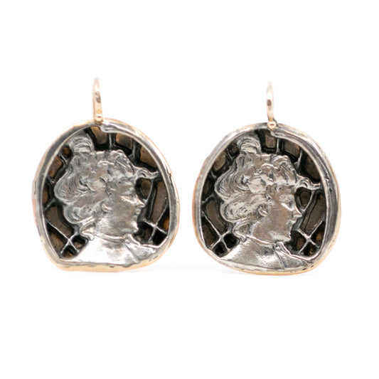 Pair of silver and gold earrings with classical portrait design on a white background