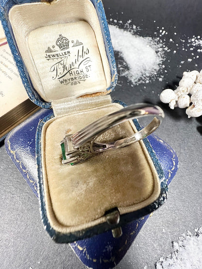 A three stone emerald and diamond ring in platinum, in an antique ring box