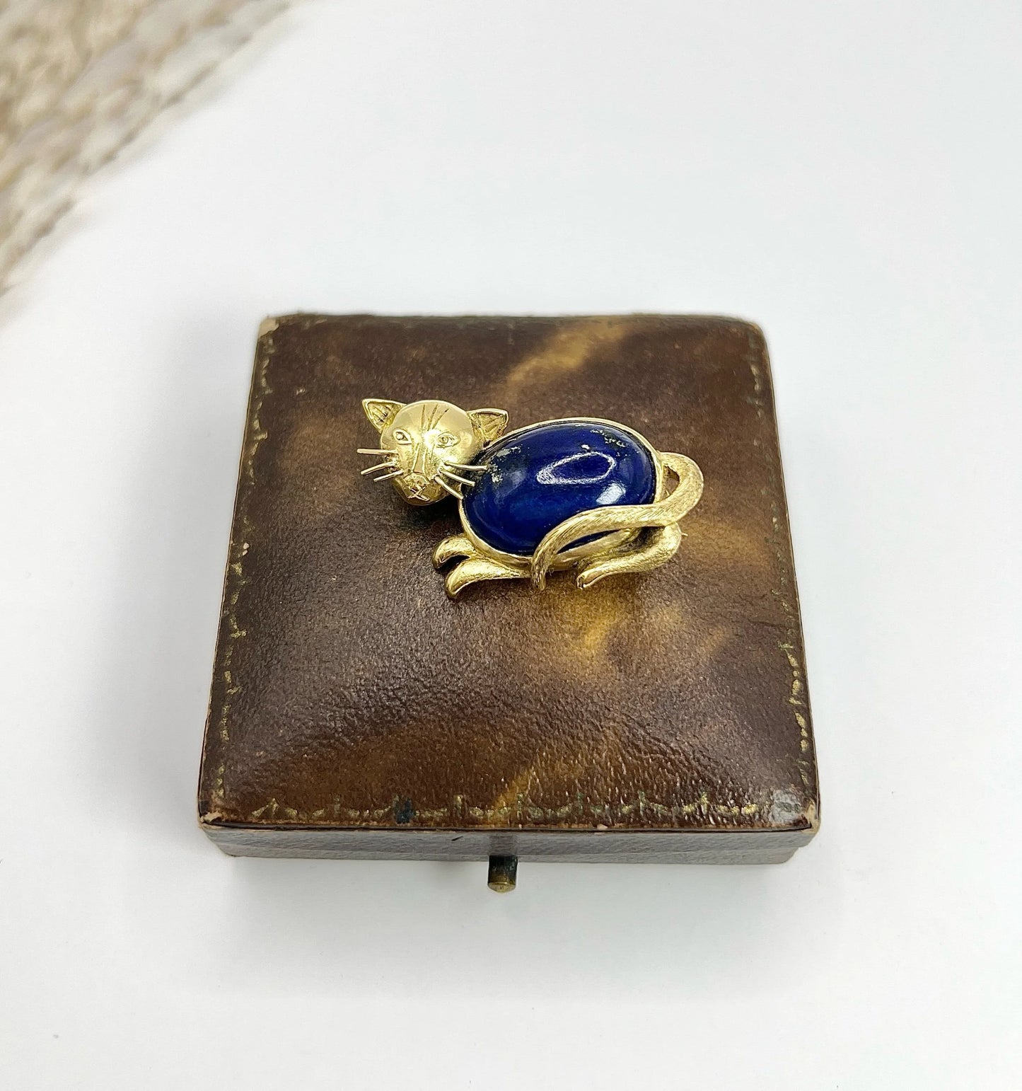 A yellow gold cat brooch with a lapis lazuli body