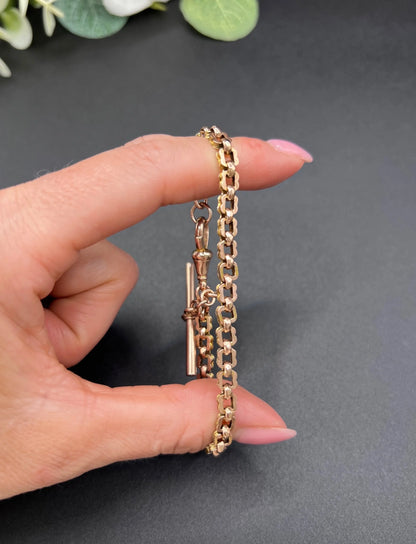 A fancy link rose gold bracelet with a T-bar and dog clip clasp, held in a hand