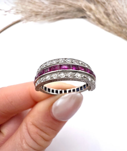 A platinum night and day flip band ring set with diamonds, sapphires and rubies, held in a hand