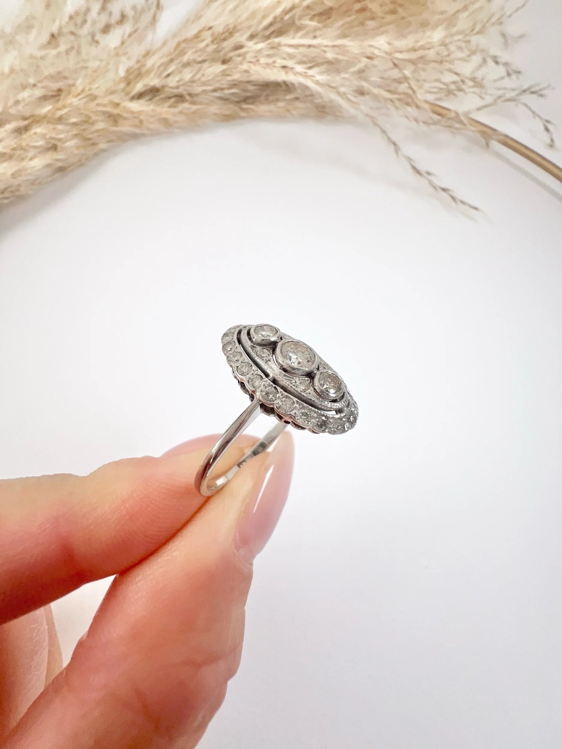 Antique 18 Carat White Gold Three Stone Diamond Oval Halo Ring, Circa 1910