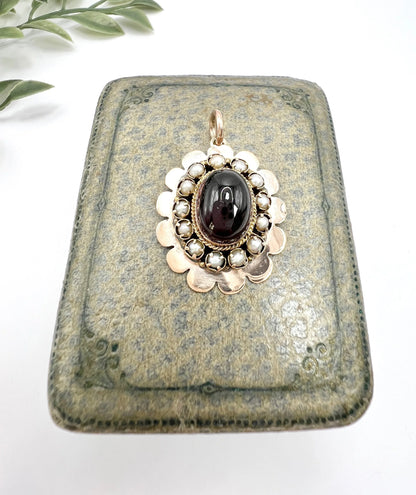 A cabochon garnet pendant with a seed pearl border in rose gold