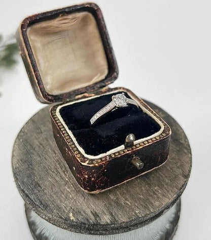 A white gold brilliant cut diamond engagement ring with diamond set shoulders, in a ring box
