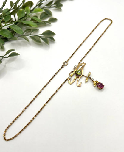 A yellow gold pendant necklace with pearls, a peridot, a diamond and a pink tourmaline drop