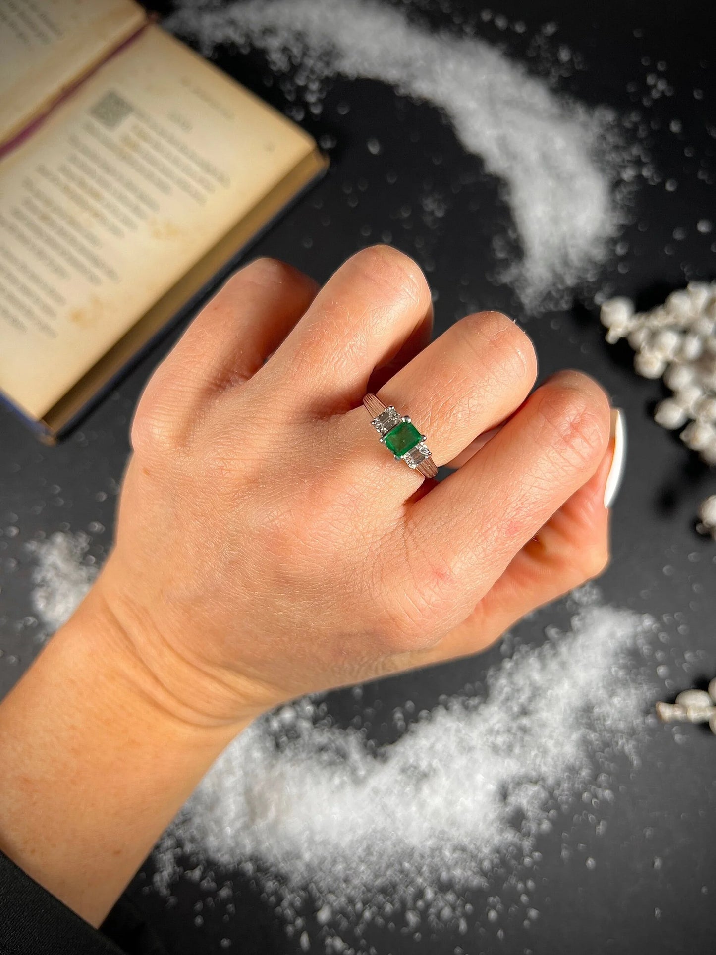 A three stone emerald and diamond ring in platinum, modelled on a hand