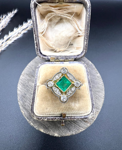 A gold and platinum ring with a centre emerald and diamond surround, in an antique ring box