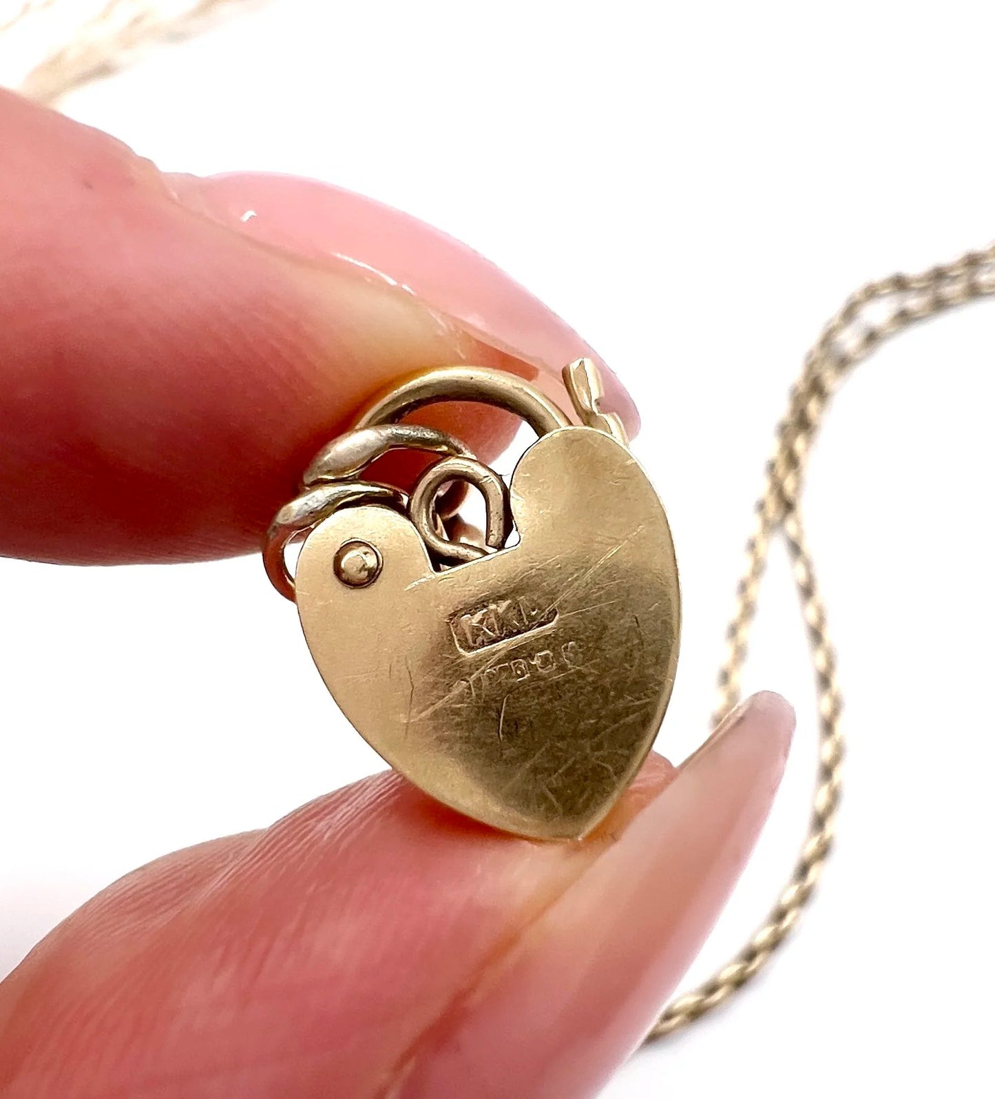 Close-up of stamps on a gold heart padlock clasp