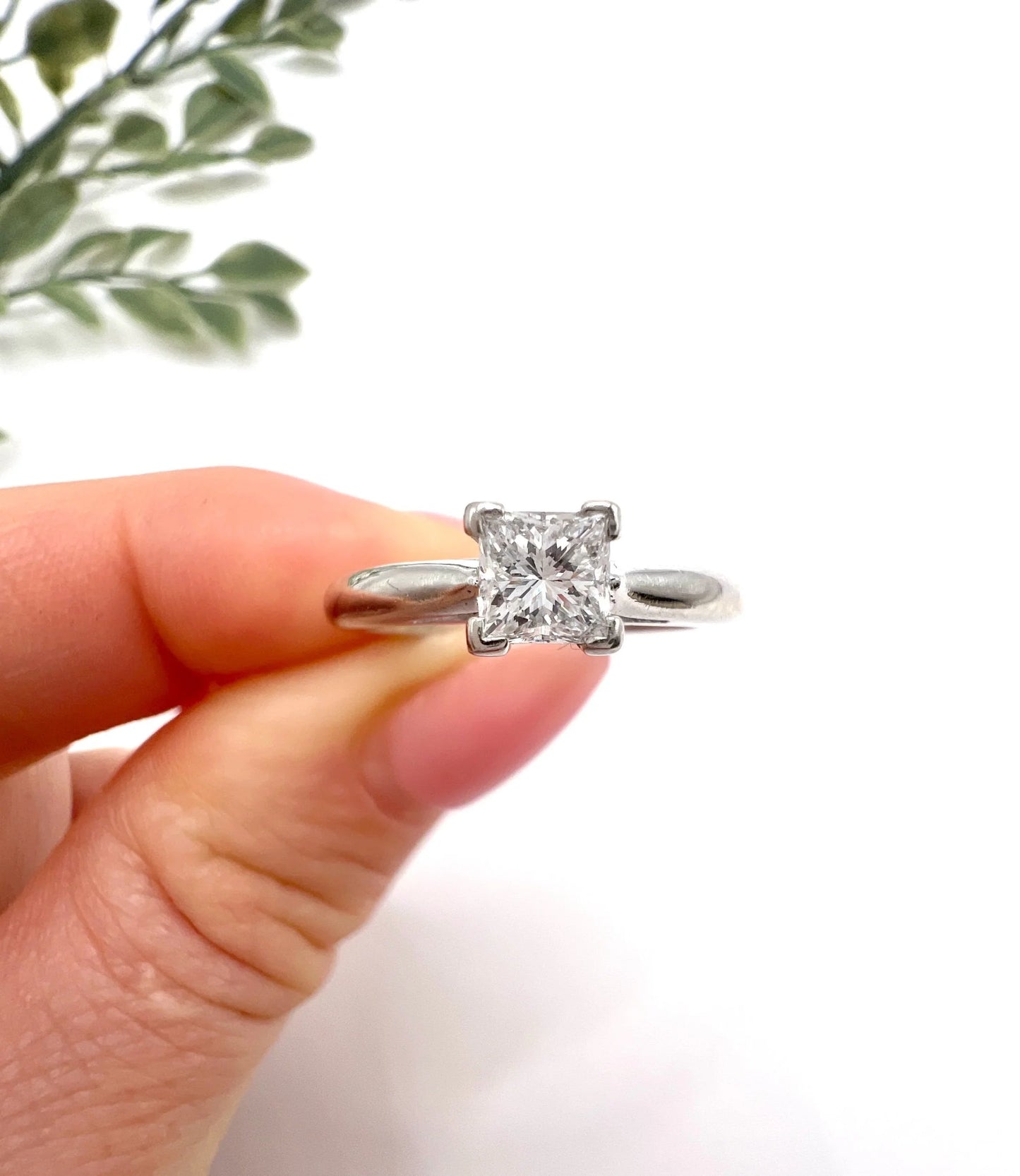 A princess cut diamond solitaire ring in platinum, held in a hand
