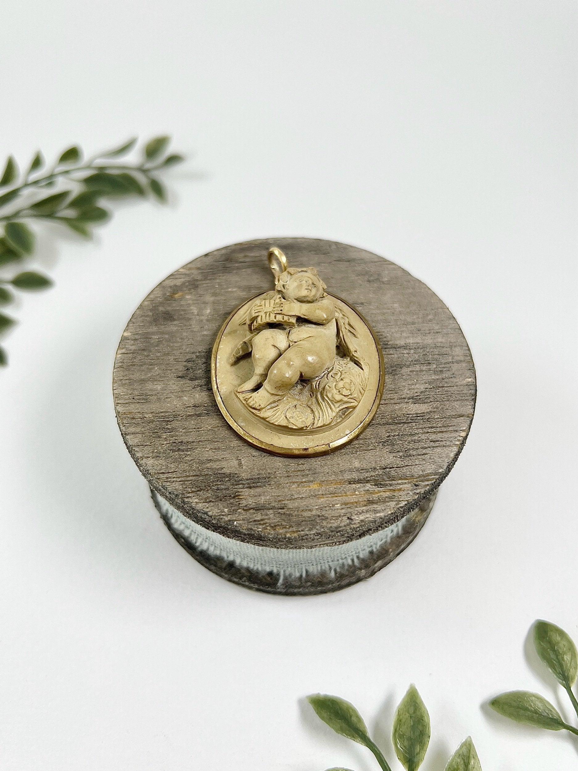 An oval cherub lava cameo pendant in yellow gold