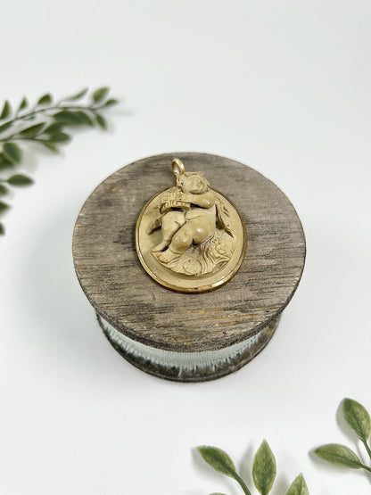 An oval cherub lava cameo pendant in yellow gold