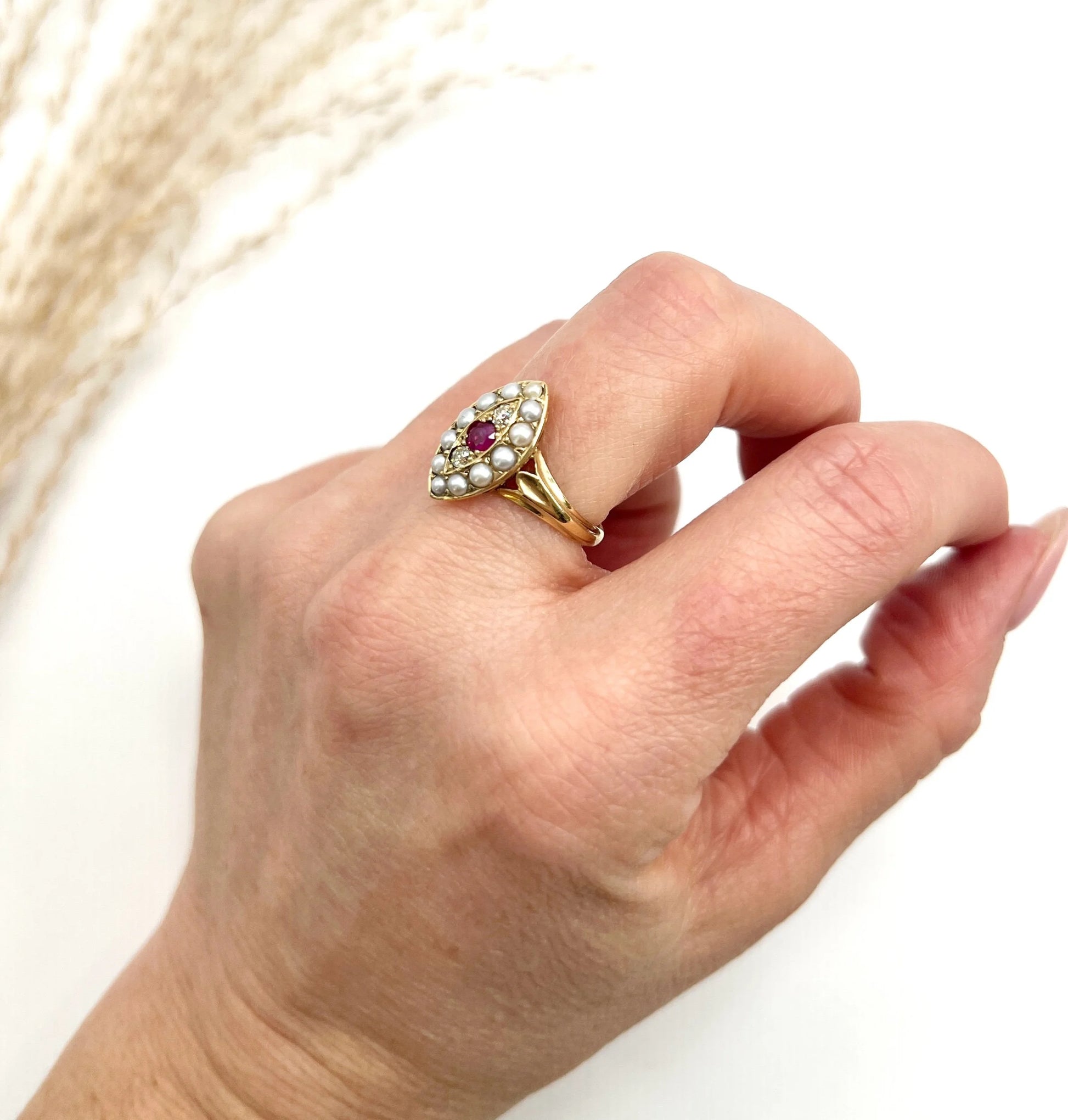 A navette shaped pearl, diamond and ruby cluster ring in yellow gold, modelled on a hand