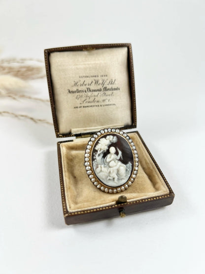 An antique oval cameo brooch depicting cherubs and birds, with a pearl border, set in gold