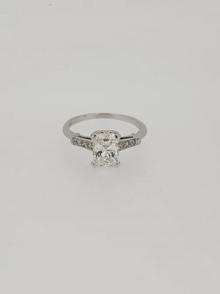 Emerald Cut Diamond Solitaire Engagement Ring; central 1.18 carat emerald-cut diamond, four-claw-set, accented with diamond set shoulders, in 18ct white gold