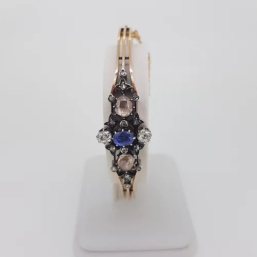 Antique Victorian Natural Sapphire and Old Cut Diamond Bangle Bracelet; central oval faceted natural sapphire surrounded by two white old-cut diamonds and two foiled pink rose-cut diamonds. Decorated with smaller rose cut diamonds