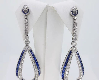 Pair of Contemporary Sapphire, Diamond and Platinum Drop Earrings; featuring calibre-cut sapphires and brilliant-cut diamonds.