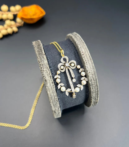 A pearl and diamond bow pendant in gold and platinum, with a chain