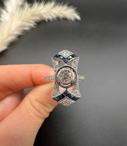 An Art Deco design sapphire and diamond ring in white gold, held in a hand