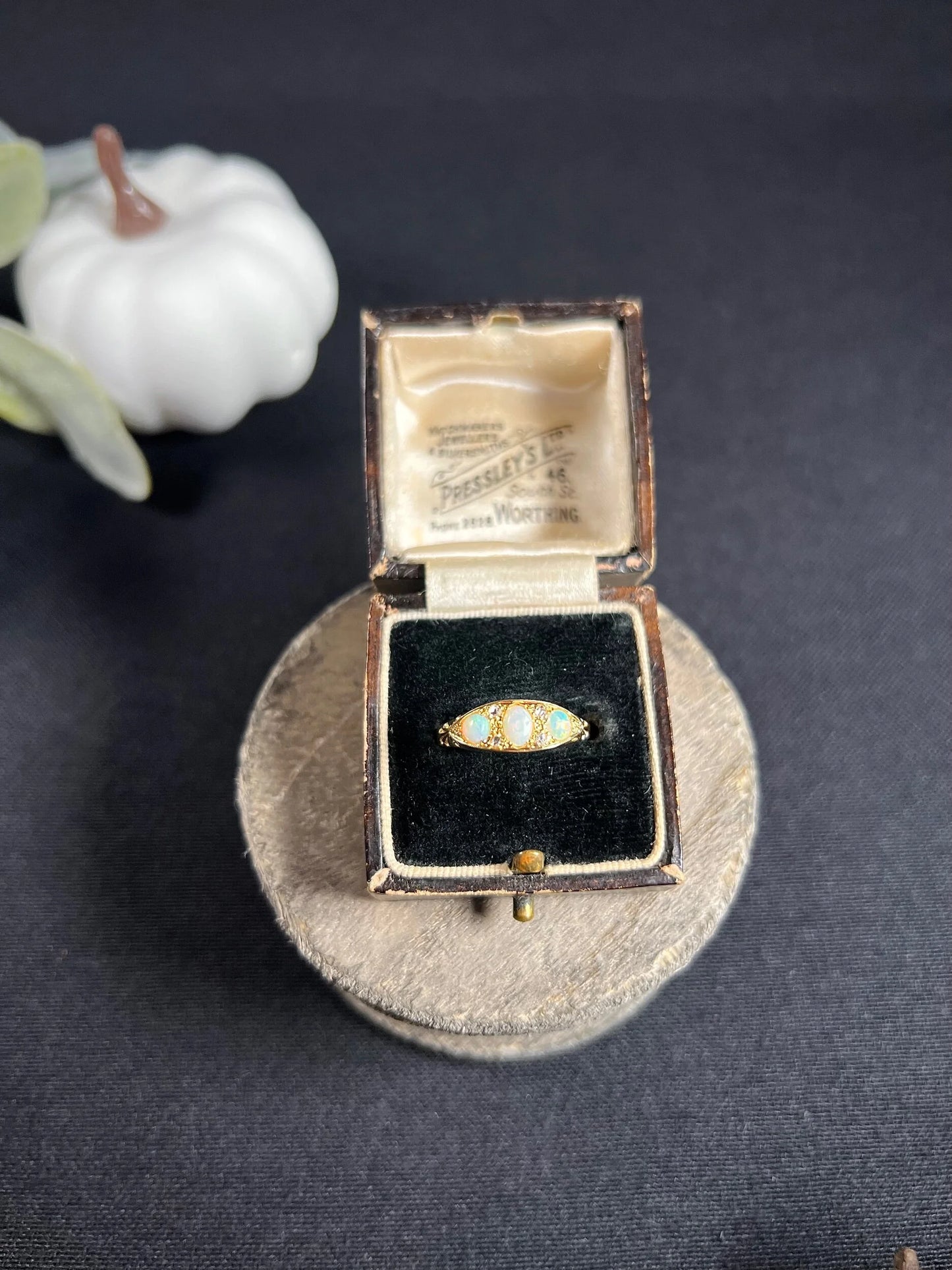 A boat-shaped gold ring with opals and diamonds, in a ring box