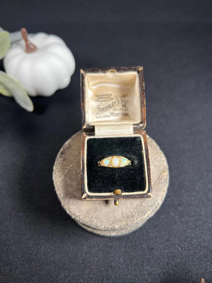 A boat-shaped gold ring with opals and diamonds, in a ring box