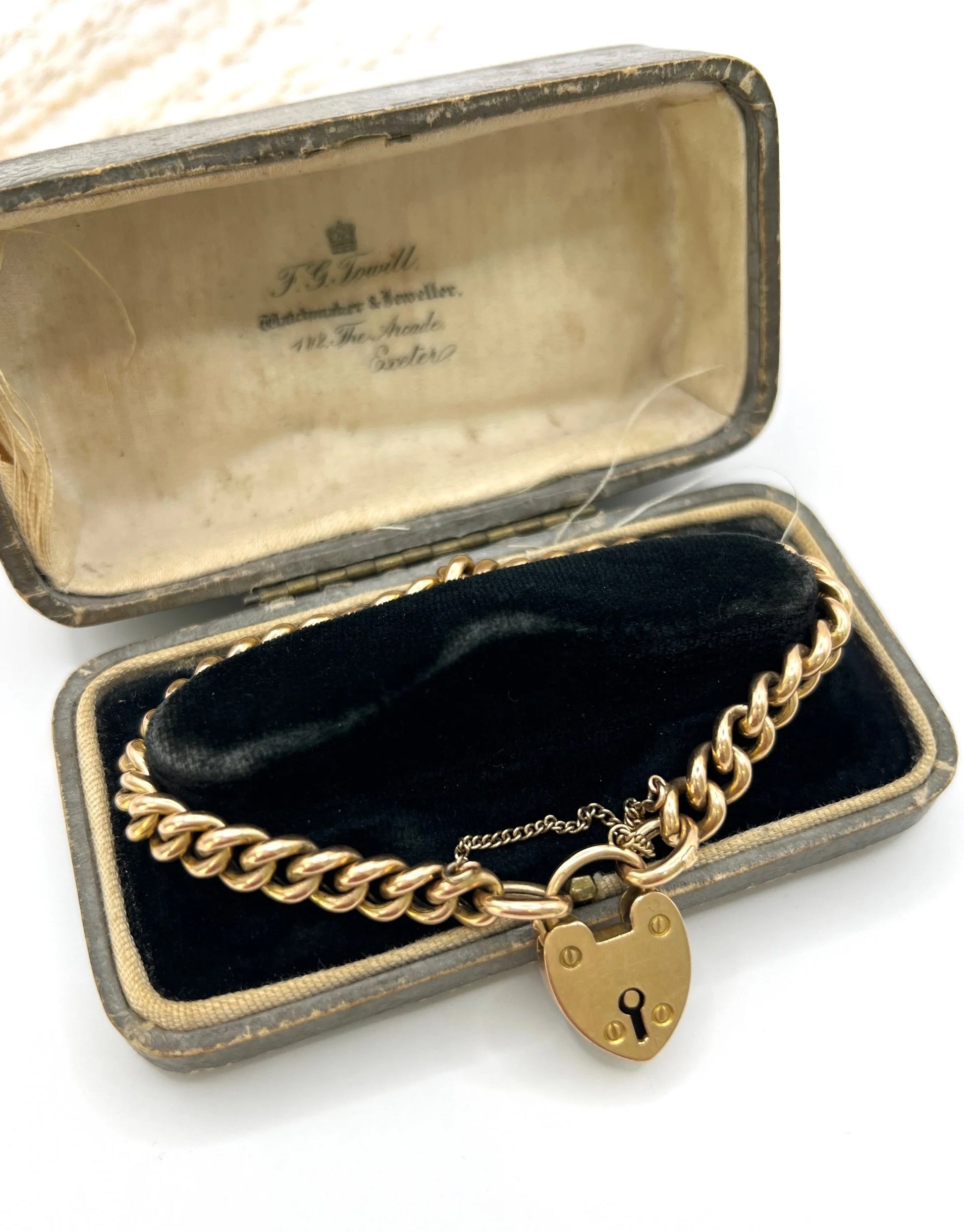 A gold curb link bracelet with heart shaped padlock, in an antique box
