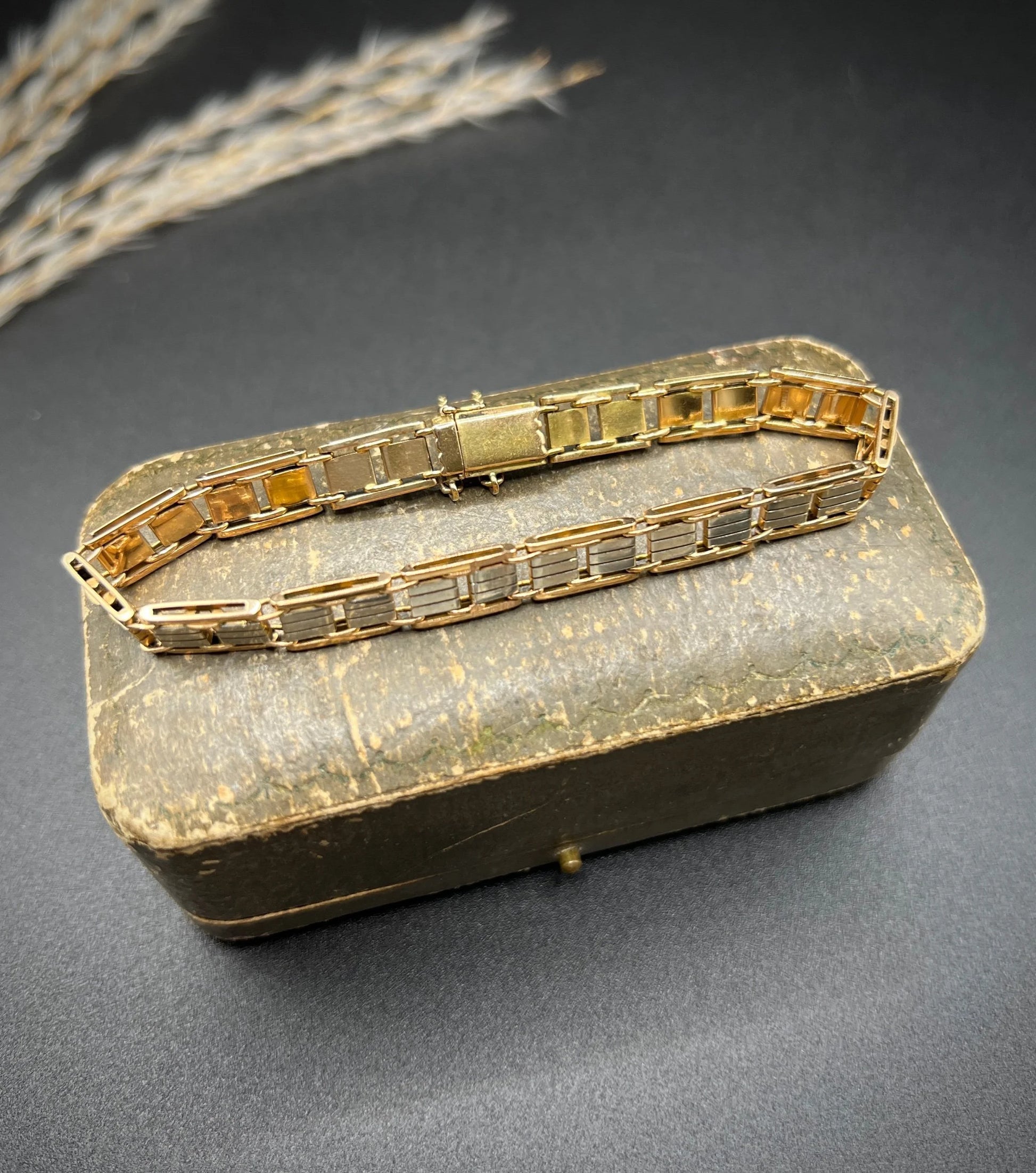 A gold and platinum gate bracelet, on an antique box