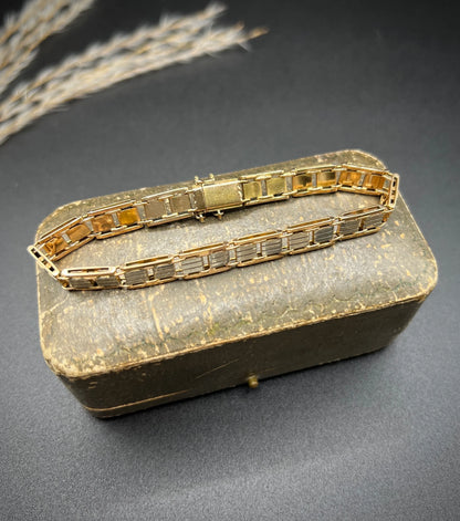 A gold and platinum gate bracelet, on an antique box