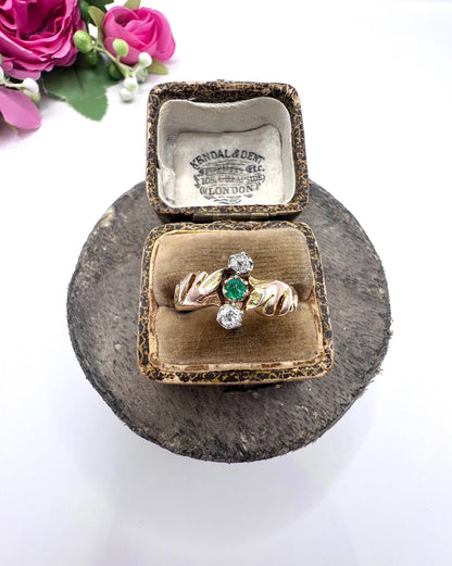 A three stone emerald and diamond ring in yellow and white gold, in an antique ring box