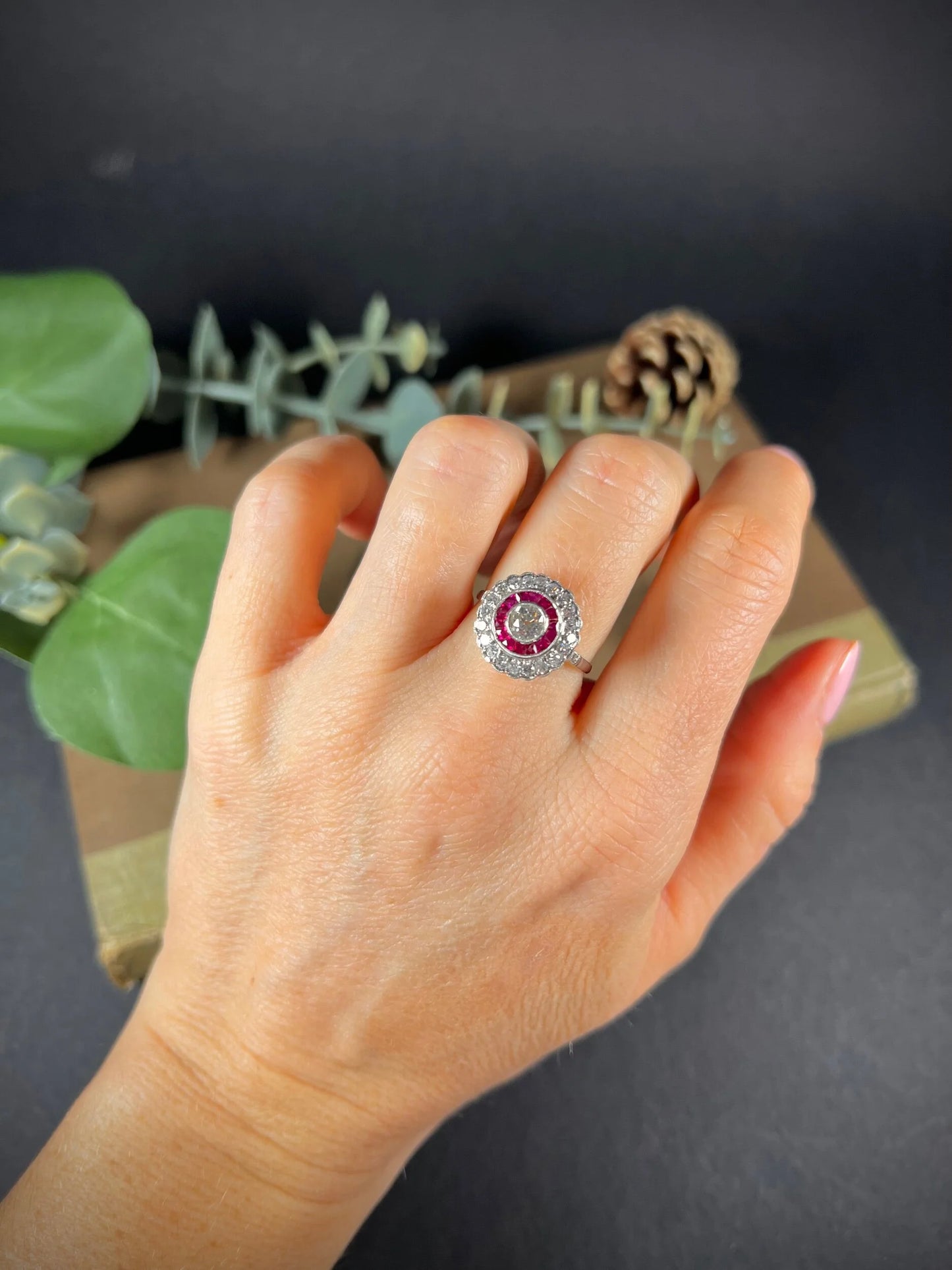 A round cluster ring with rubies and diamonds in white gold, modelled on a hand