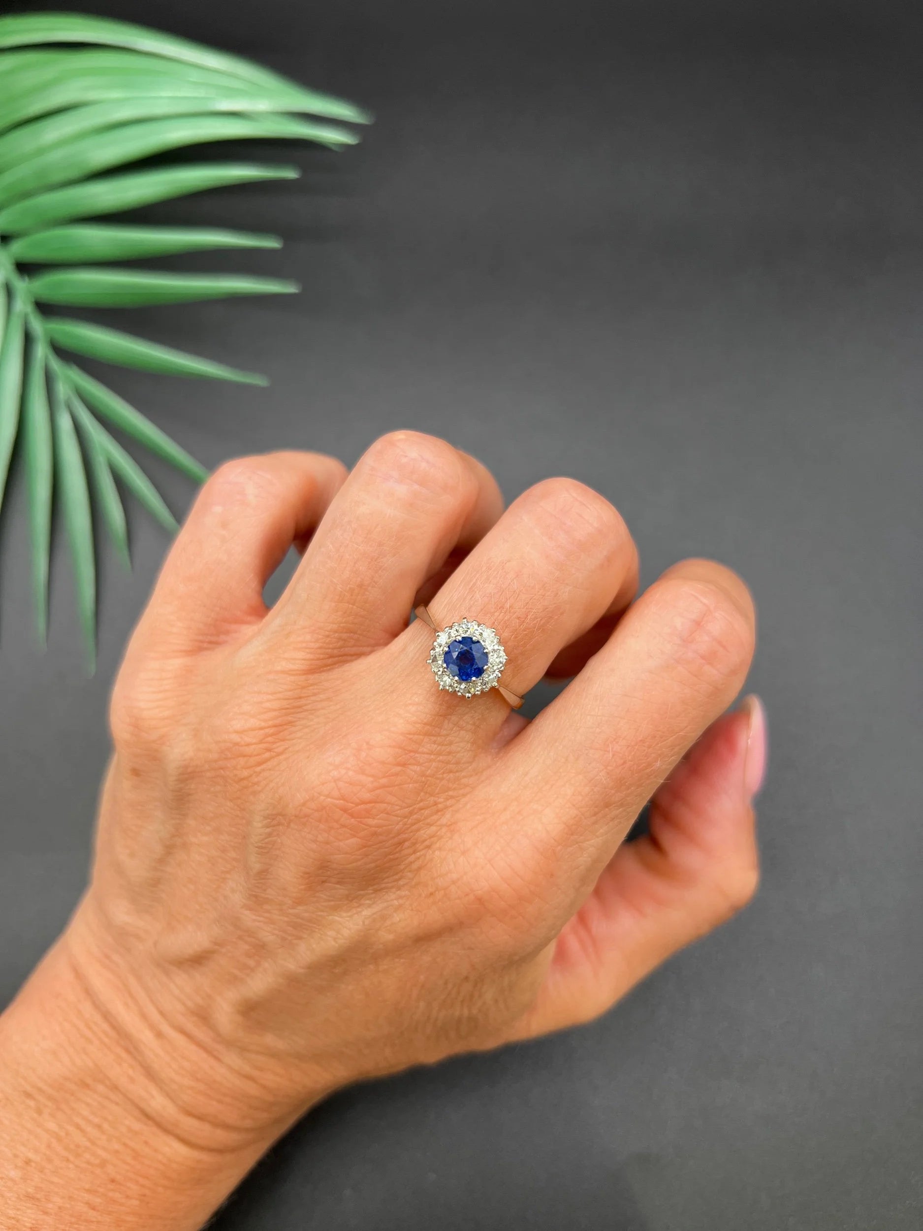 A circular cluster ring with sapphire and diamonds in yellow gold and platinum, modelled on a hand
