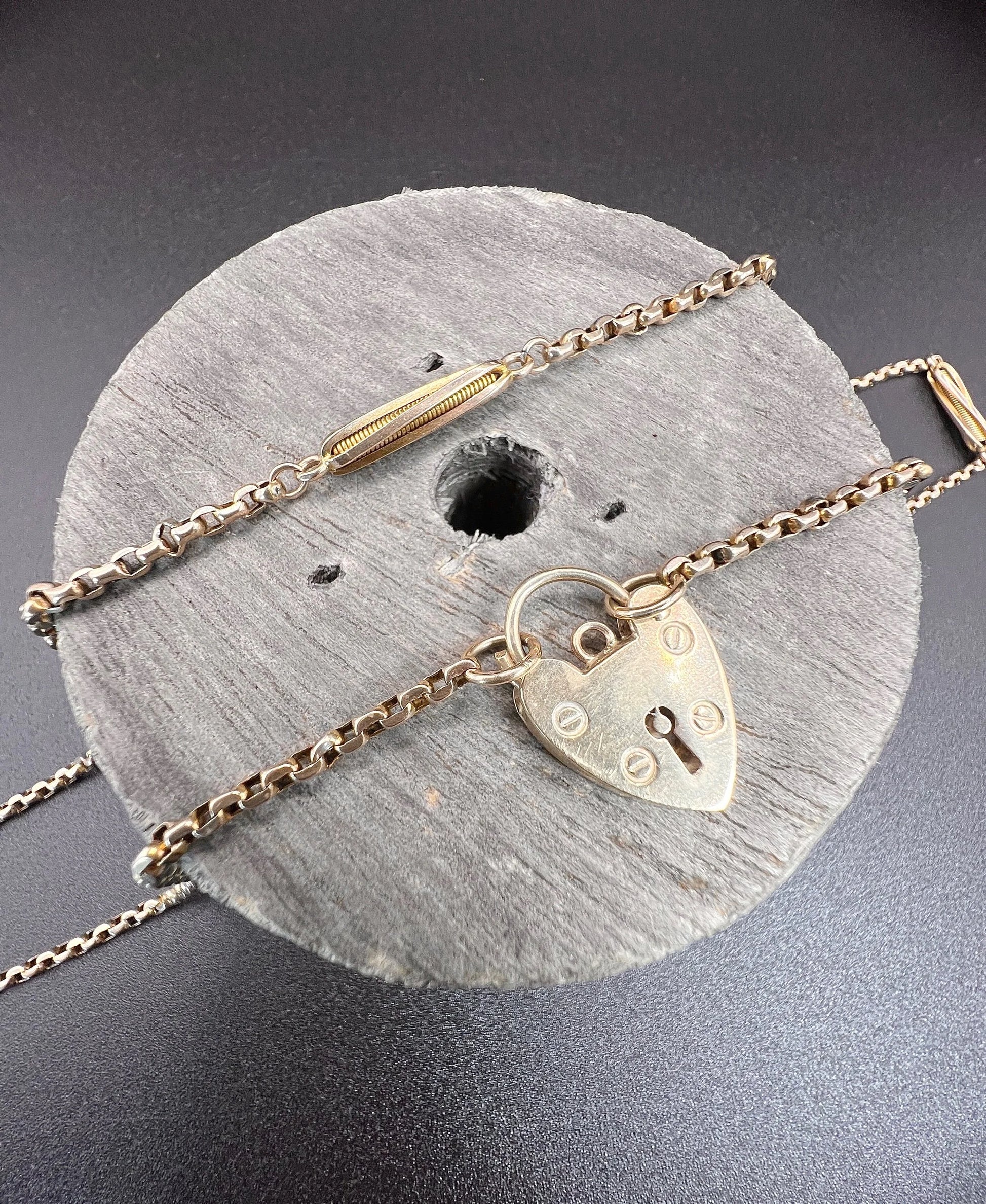 A yellow gold fancy link chain with a heart padlock