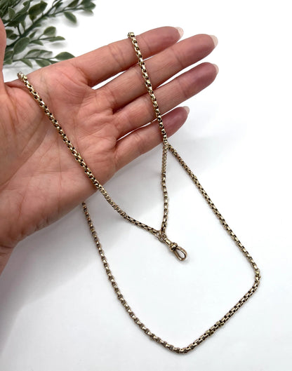 A long rose gold link necklace with swivel clasp, held in a hand
